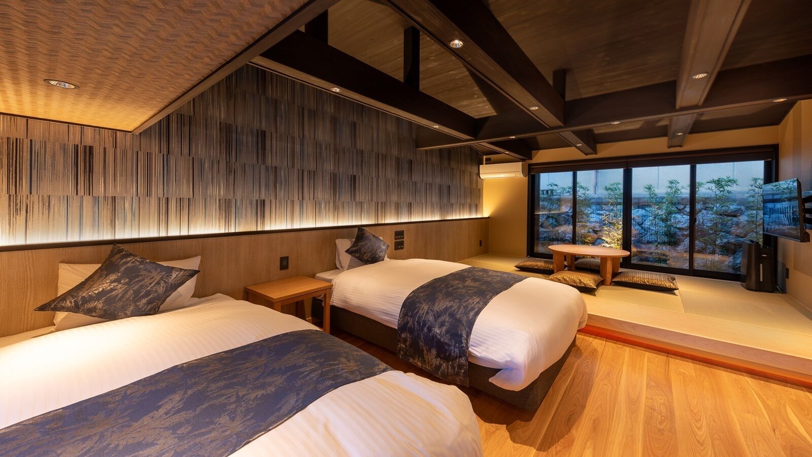 A modern hotel room with two beds, a wooden ceiling, and a large window with a view.