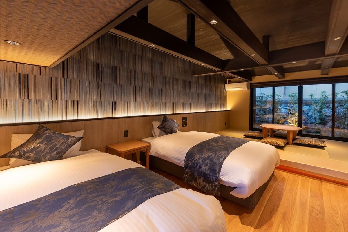 Une chambre d’hôtel moderne avec deux lits, un plafond en bois et une grande fenêtre donnant sur un beau paysage.