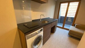 Une cuisine compacte équipée d’un lave-linge, d’un évier et d’un four encastré.