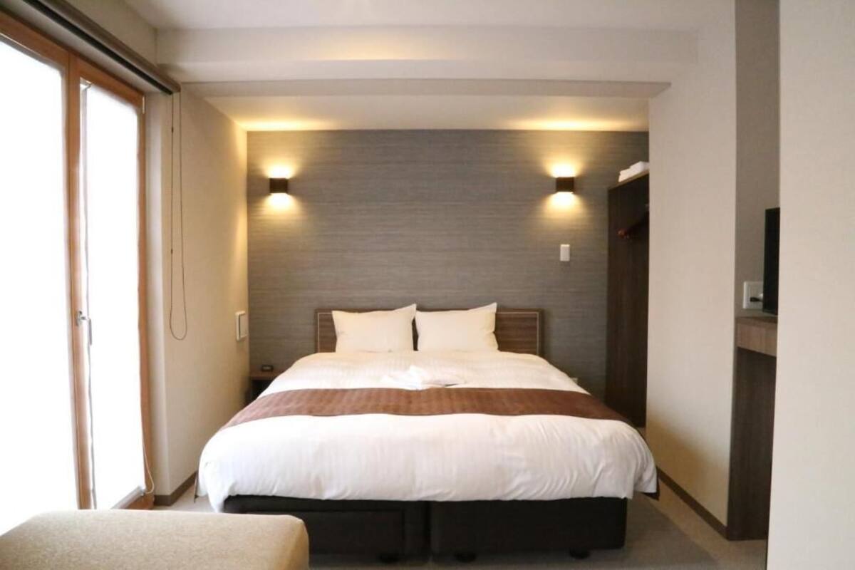 A hotel room with a large bed, two bedside tables, a wardrobe, and a television.