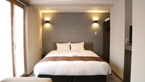 Une chambre d’hôtel avec un grand lit, deux tables de chevet, une armoire et un téléviseur.