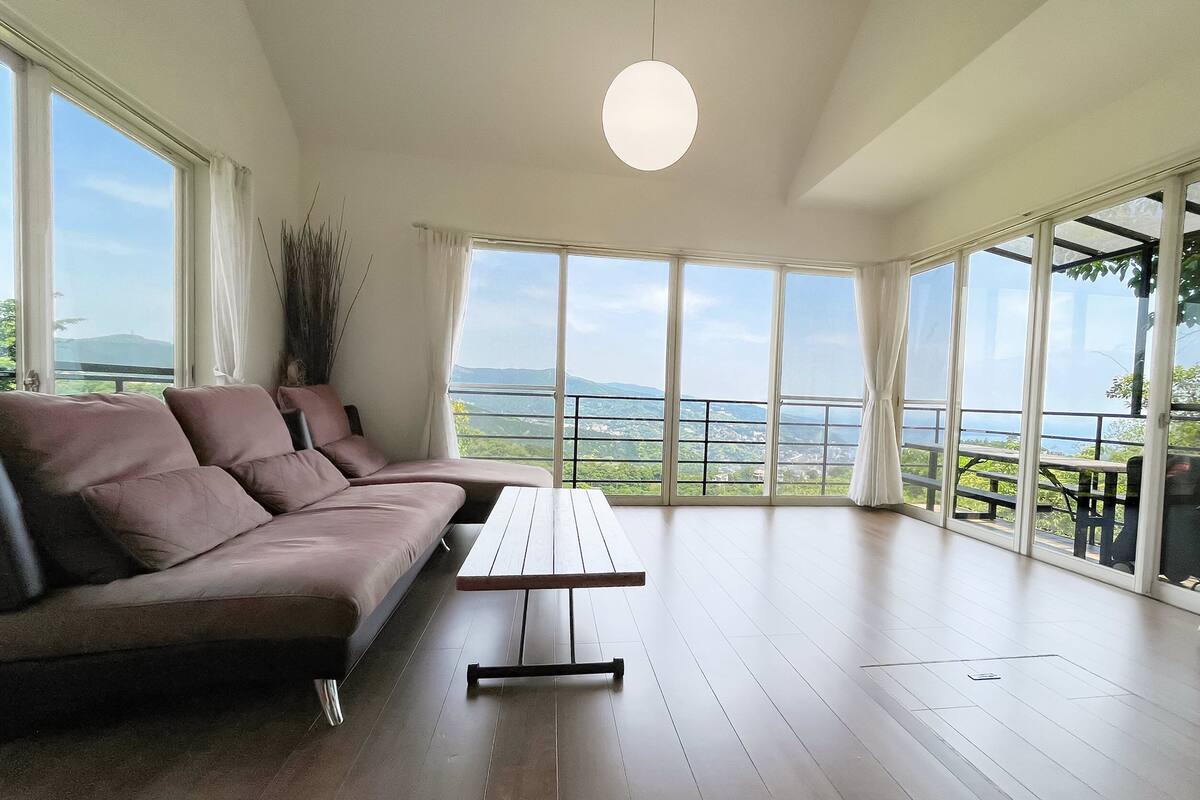 A spacious room with a large window, a sofa, and a wooden table.