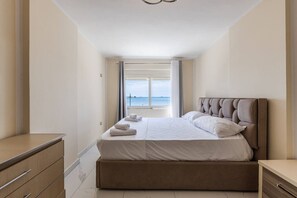 A bedroom with a bed, a view of the sea, and a window. - Sea View Apartment | Durrës Waterfront by PikHost (Durrës)