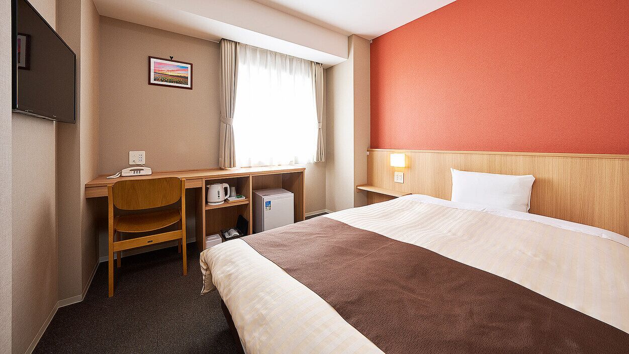 Una habitación de hotel con cama, escritorio, silla y televisor.