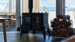 A room with a wood-burning stove, a stack of firewood, and a view of the outdoors. - Higashikawa Perican (Higashikawa)