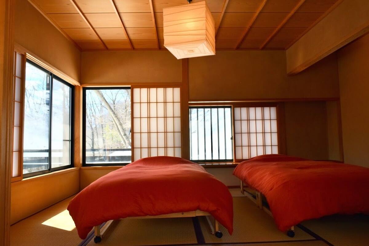Una habitación japonesa tradicional con suelo de tatami, paredes divisorias de papel y un futón.