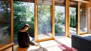 A room with large windows, a wooden floor, and a person sitting at a table. - Morihaku (Karuizawa)