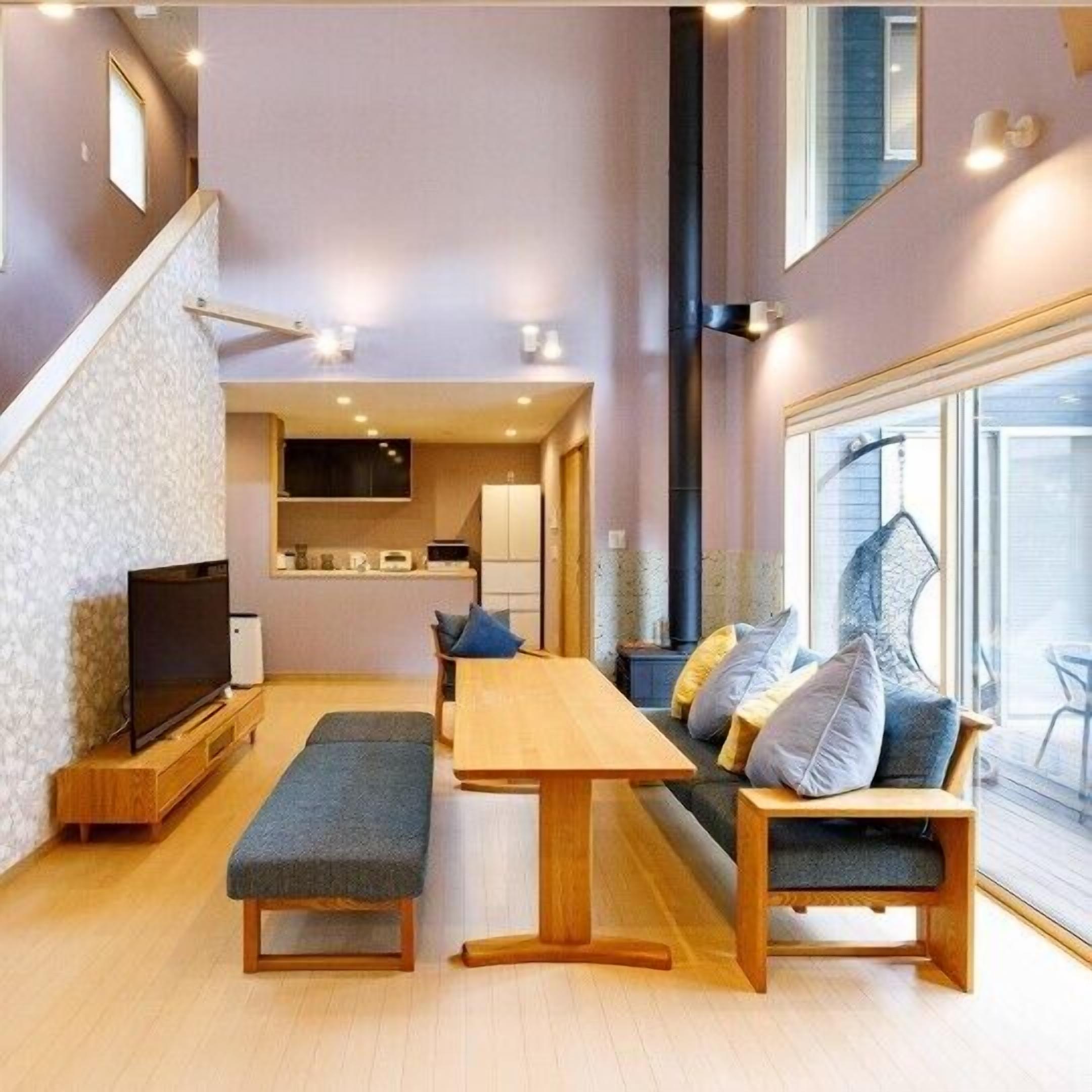 A modern living space with a TV, seating area, and a kitchen in the background.