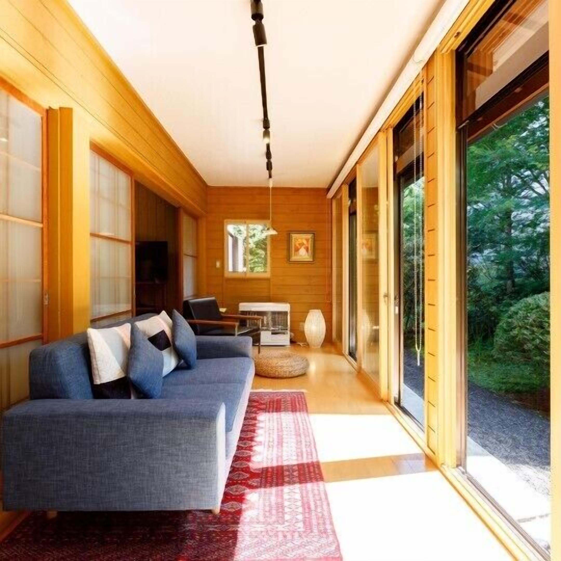 A modern interior with a sofa, a table, and a view of greenery.