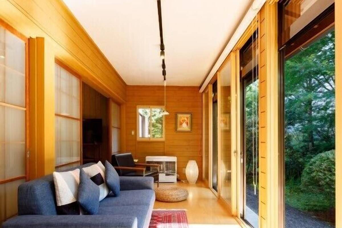 A modern interior with a sofa, a table, and a view of greenery.