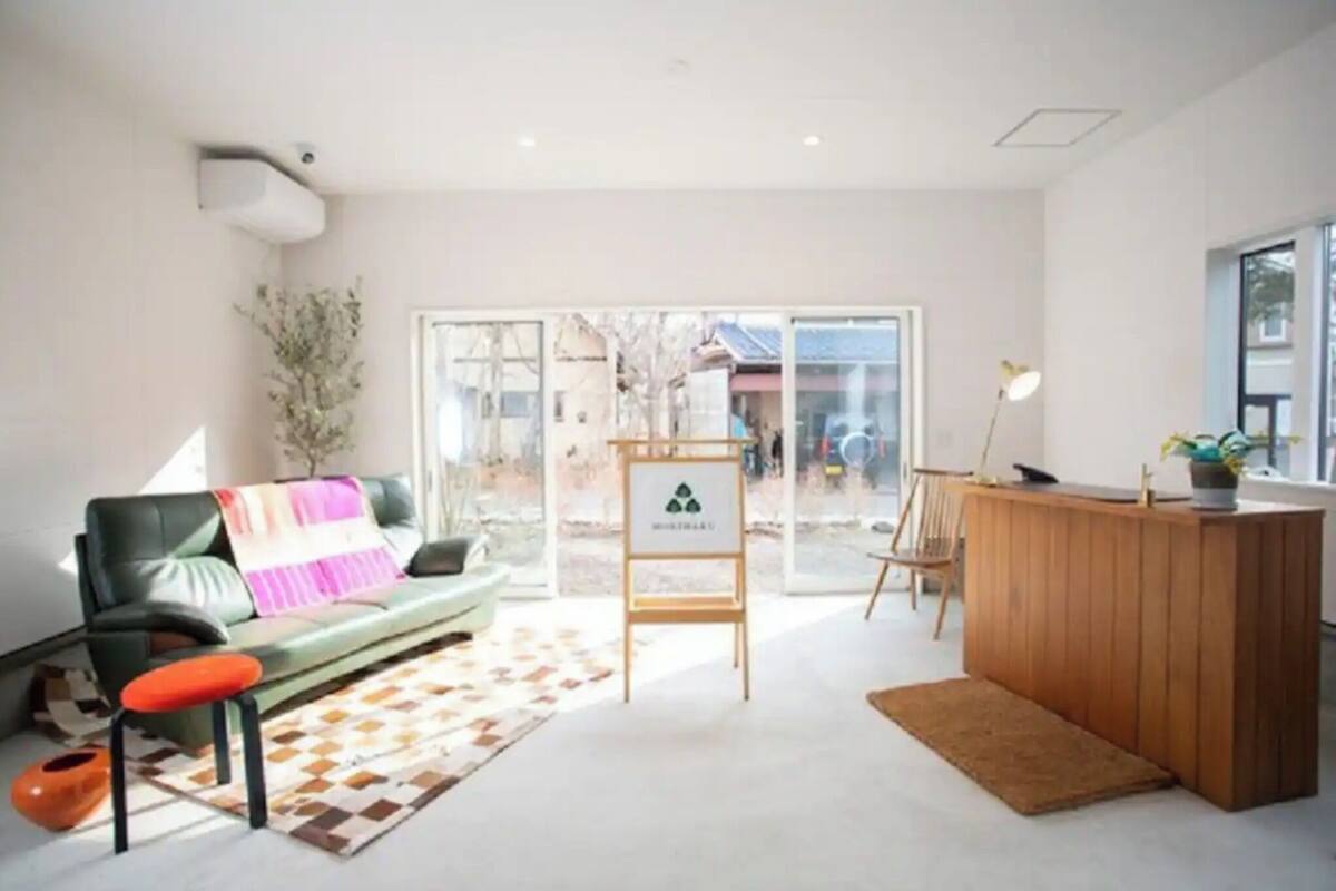 A modern interior with a sofa, a wooden reception desk, and a large glass door leading outside.
