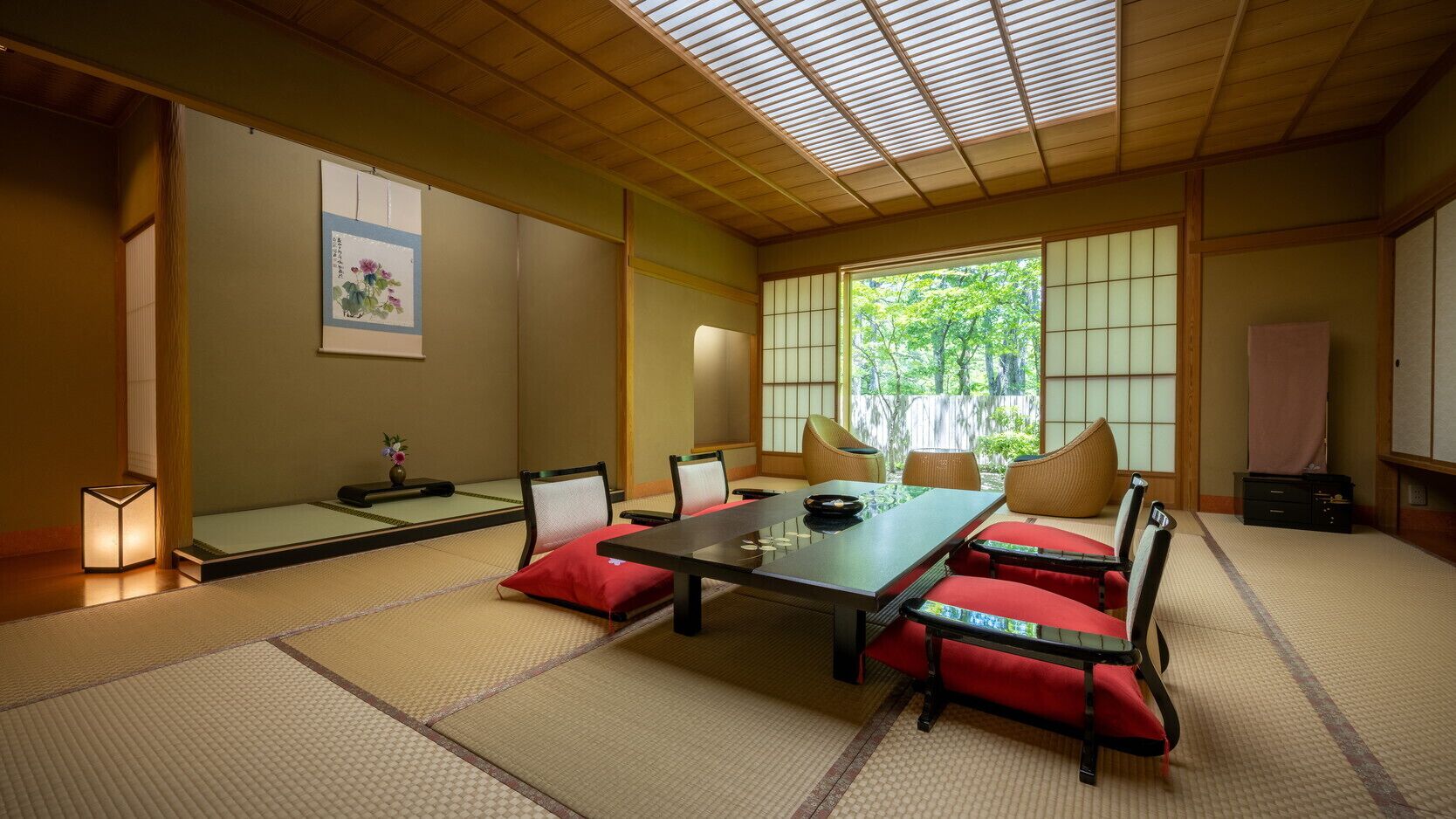 Una habitación japonesa tradicional con suelo de tatami, una mesa baja y cojines rojos.