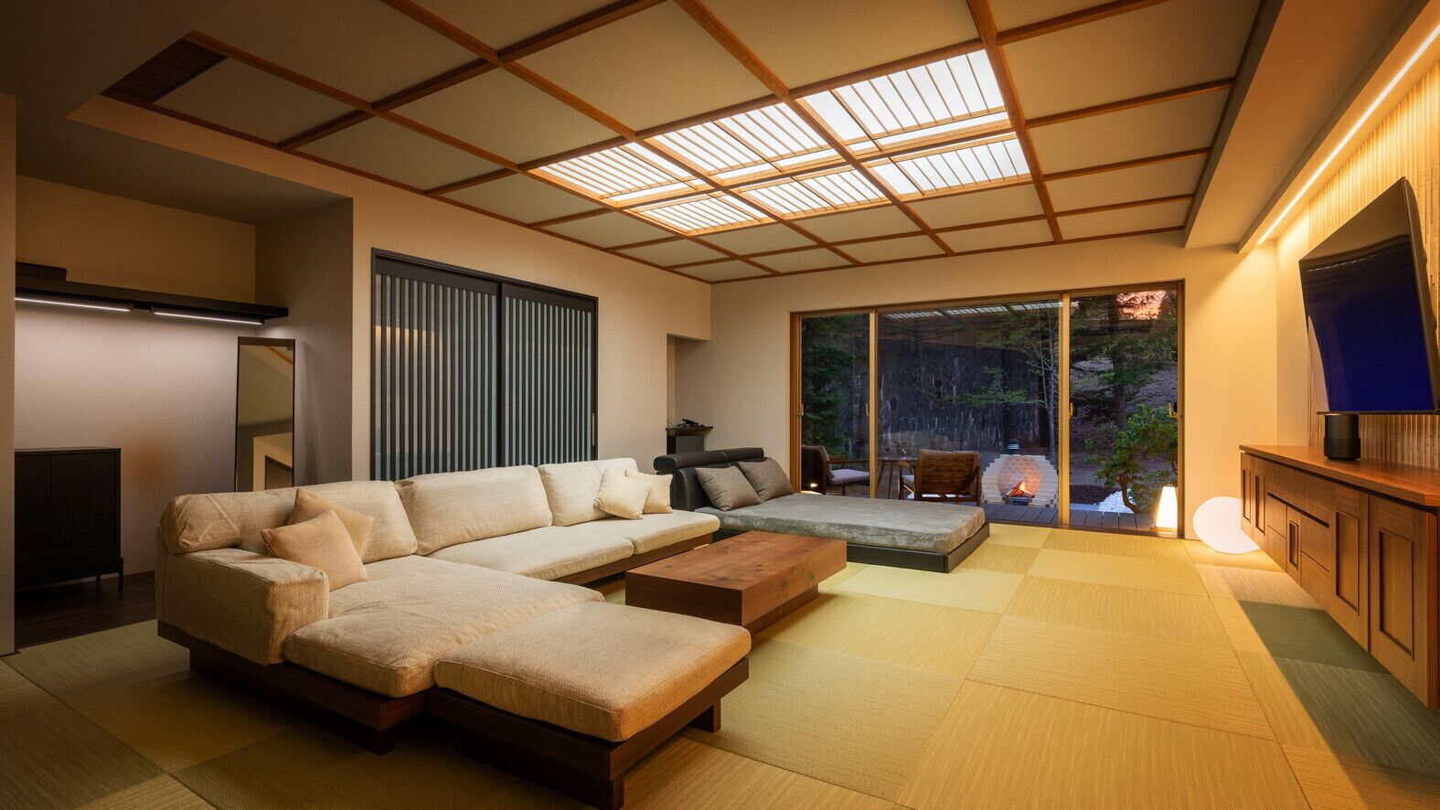 Una sala de estar moderna con un sofá modular, una mesa de centro de madera y un televisor sobre un mueble de madera.
