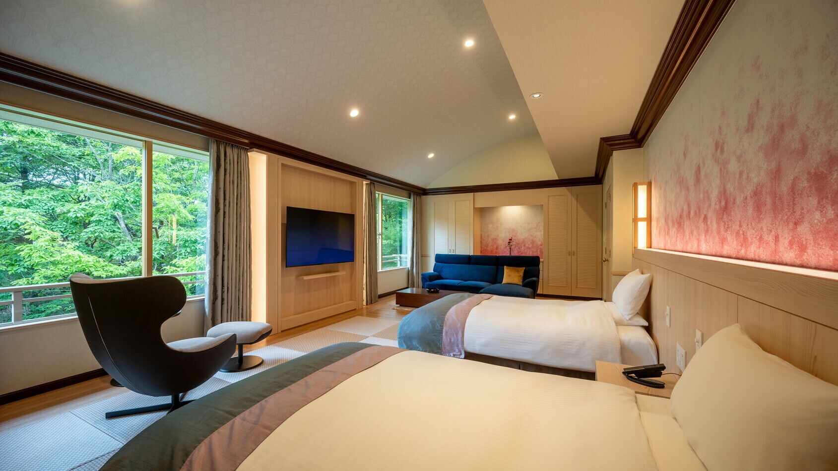 Habitación de hotel con una cama grande, un sofá, televisión y vistas a zonas verdes.