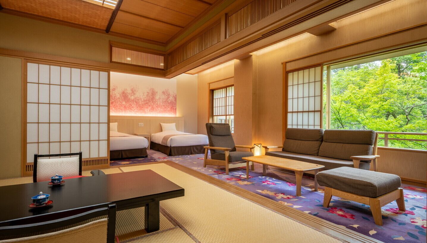 Una habitación tradicional japonesa con suelo de tatami, una mesa baja y un sofá.