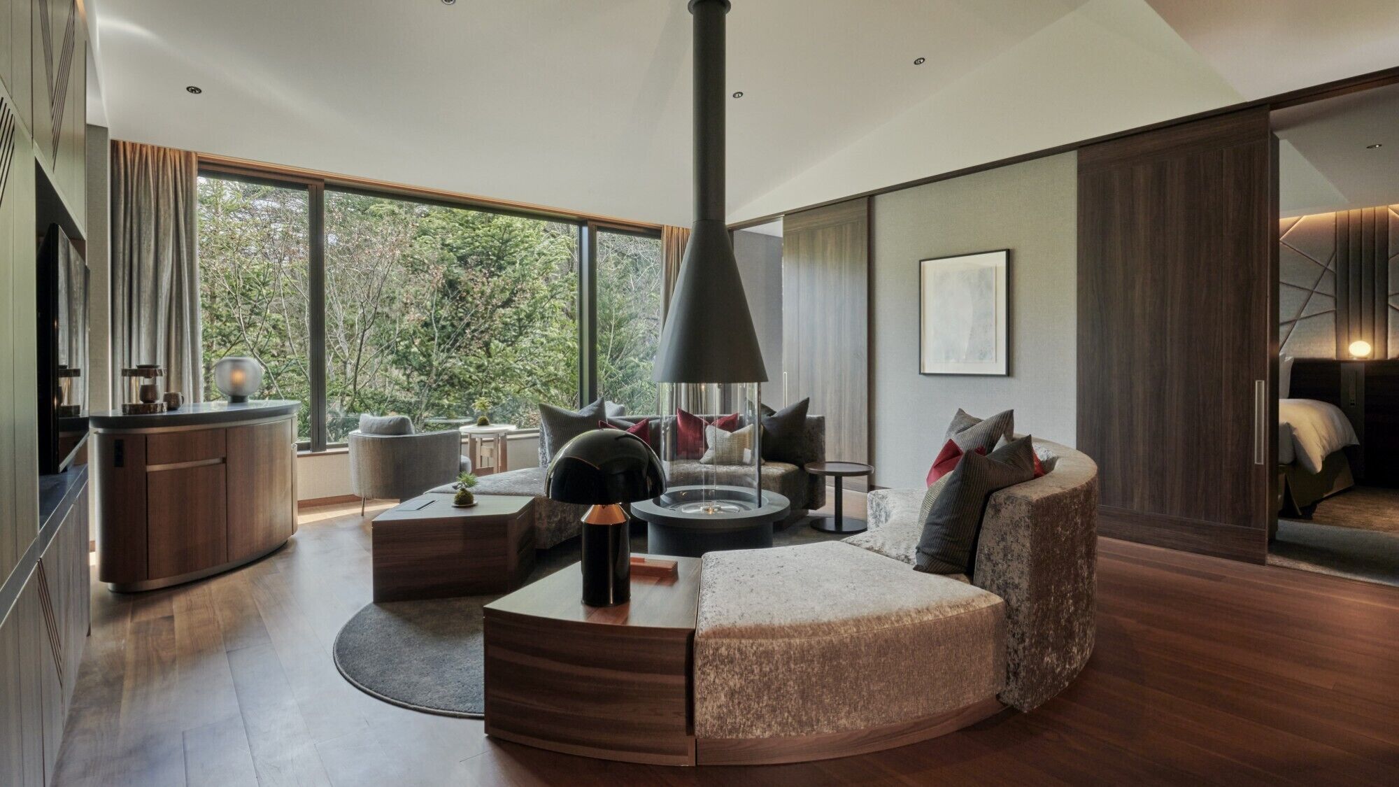 A modern living room with a fireplace, large windows, and a cozy seating area.