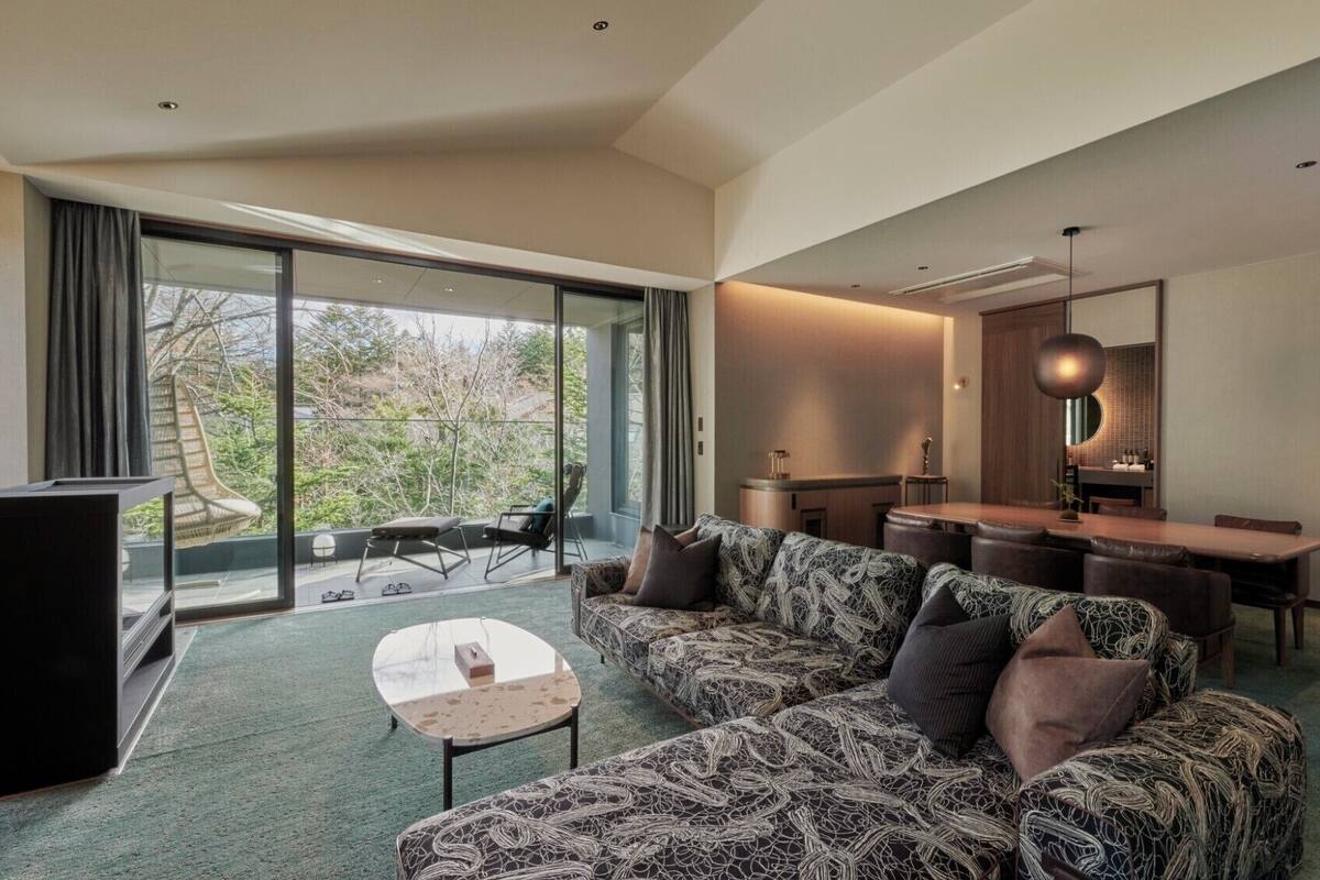 Uma sala de estar moderna com sofá, mesa de centro, televisão e área de jantar com mesa e cadeiras.