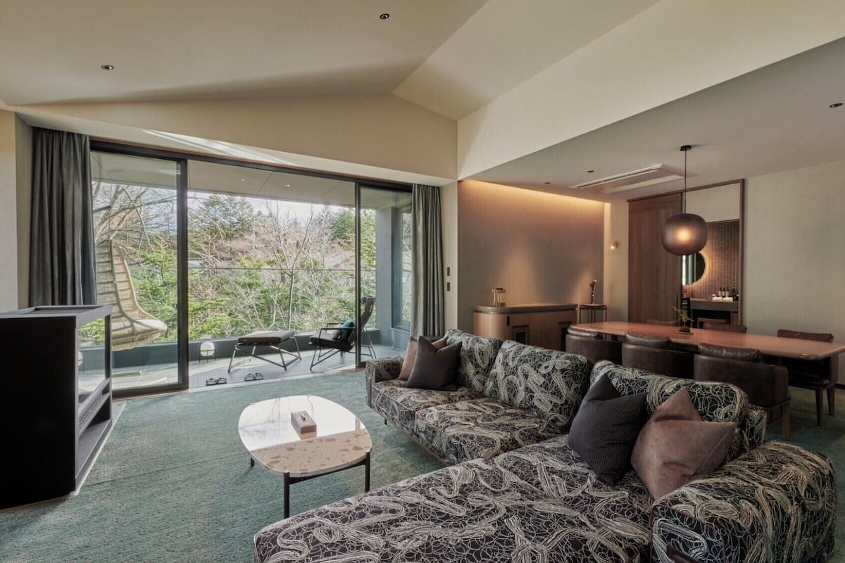 A modern living room with a sofa, a coffee table, a TV, and a dining area with a table and chairs.