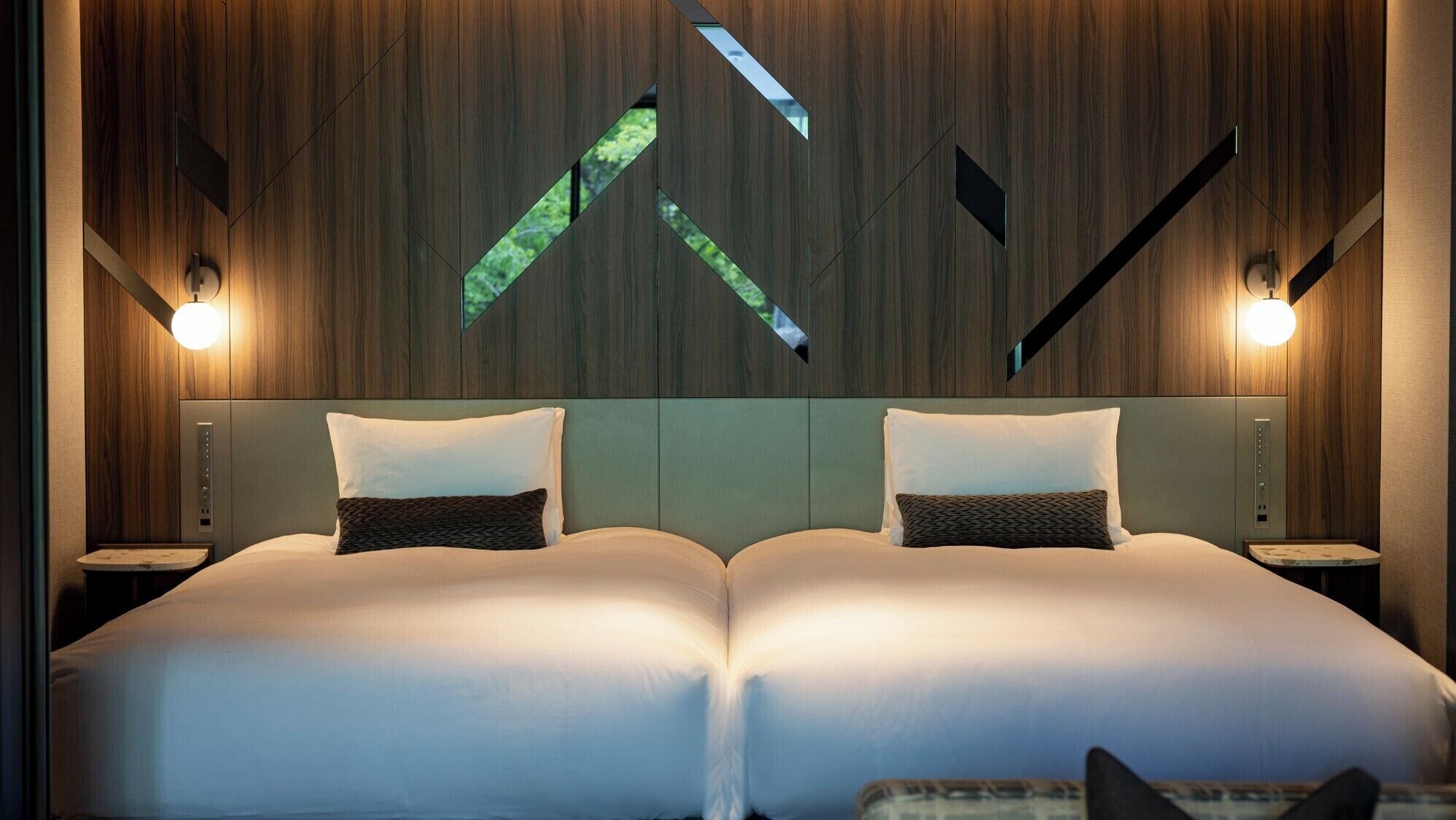 A double bed with a headboard, two bedside tables, and a wall with geometric patterns.