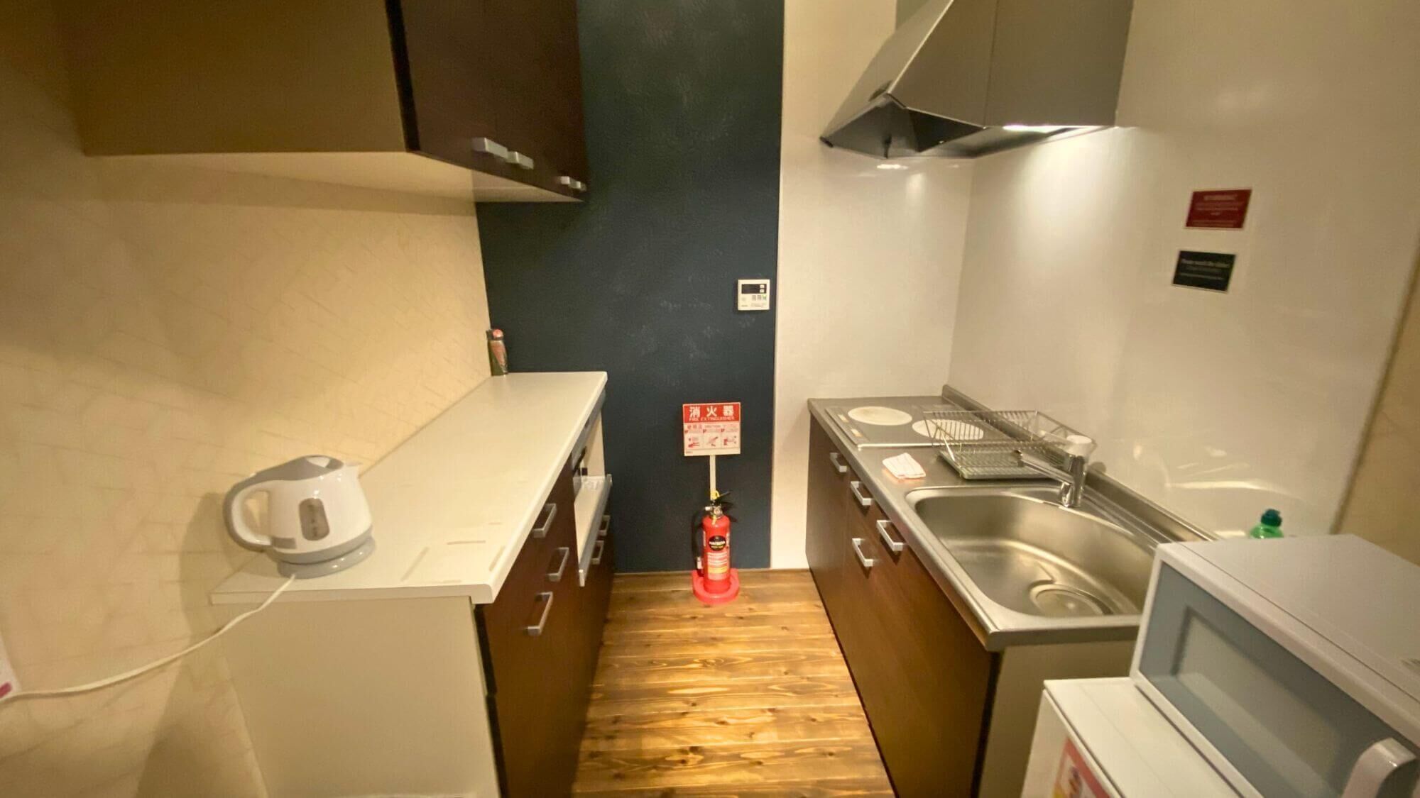 A compact kitchen with a microwave, sink, and kettle.