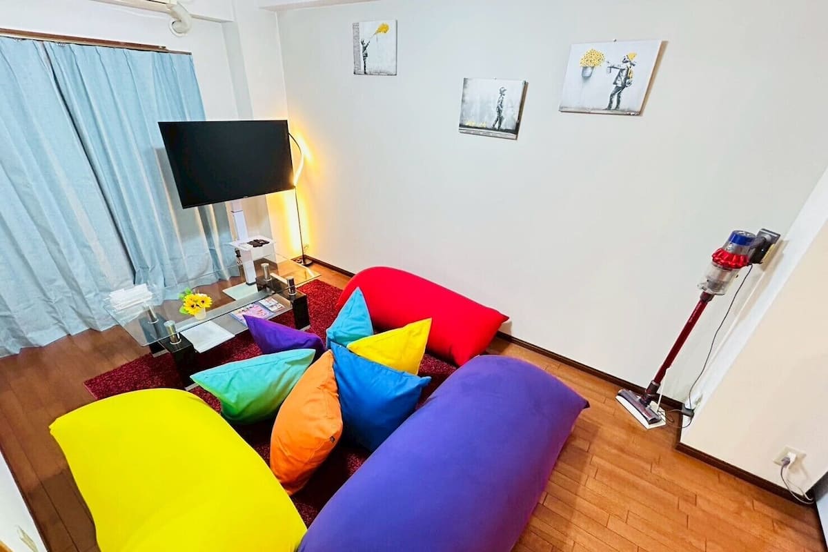 A living room with a sofa, a flat-screen TV, a coffee table, and a lamp.