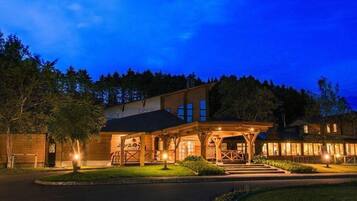 A two-story building with a covered porch and a well-lit entrance.