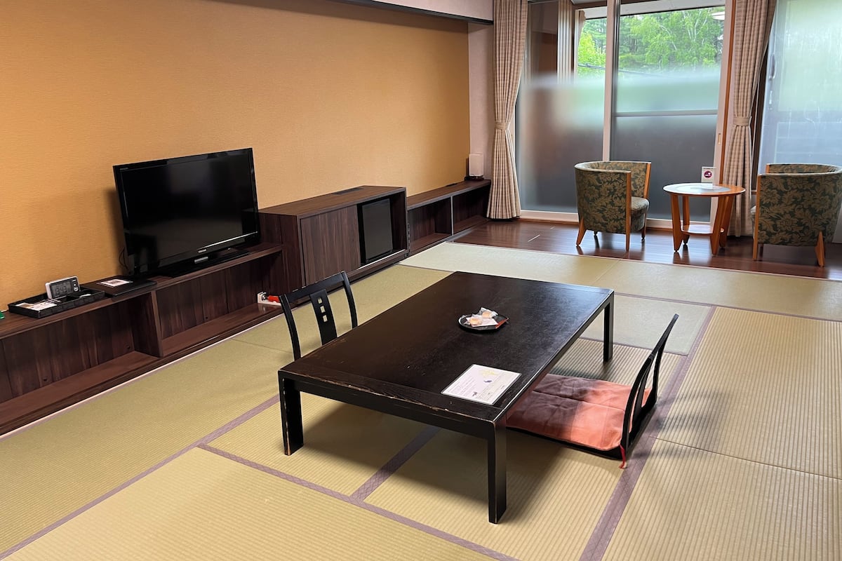 Habitació amb paviment de tatami, televisió, taula amb safata i porta corredissa amb vista.