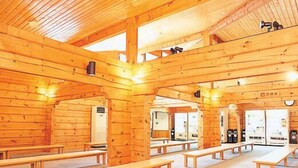 A wooden cabin with multiple benches and a central fireplace. - Yunni no Yu (Yuni)