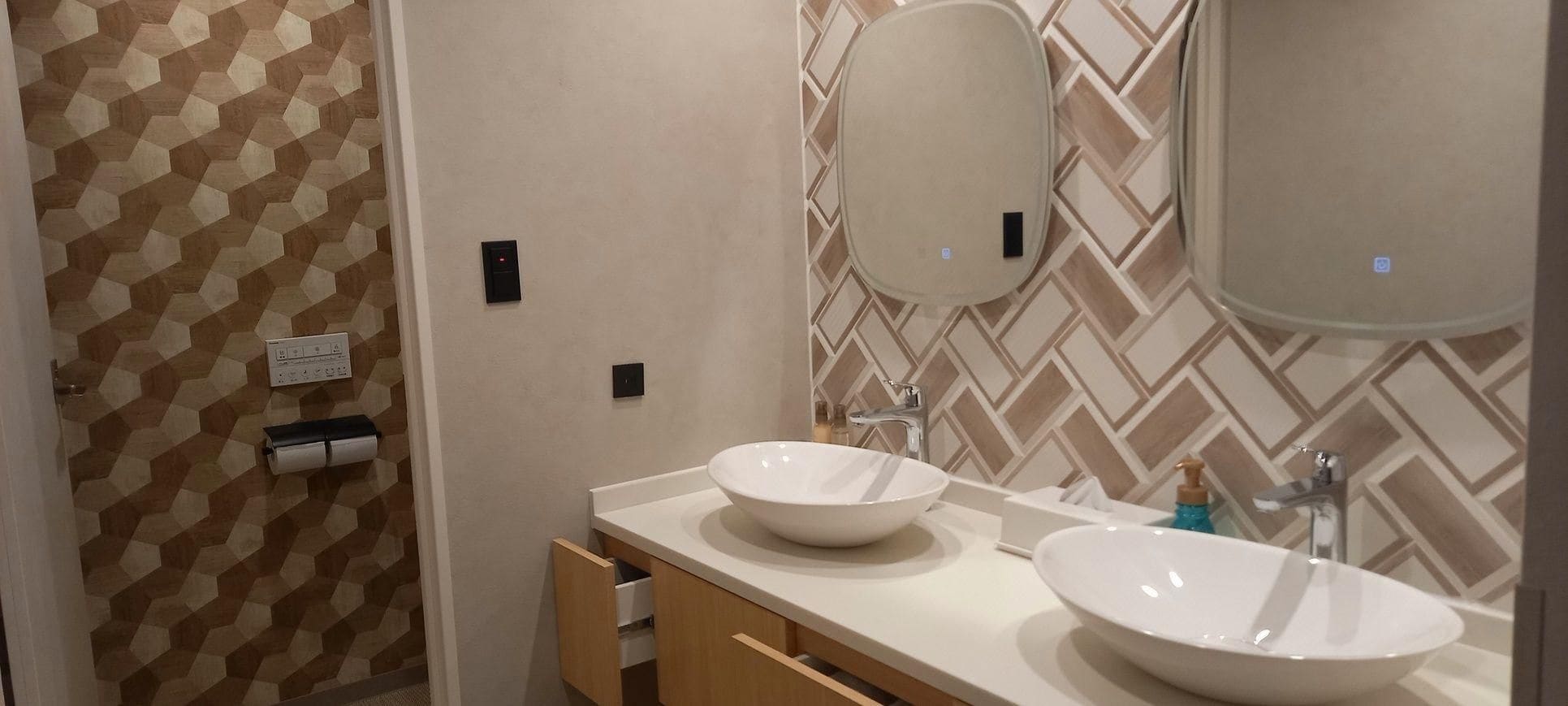 A bathroom with two sinks, a mirror, and a towel dispenser.