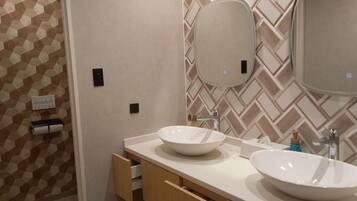 A bathroom with two sinks, a mirror, and a towel dispenser.
