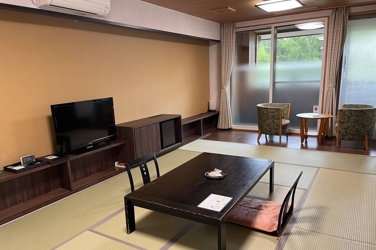 Una habitació amb paviment de tatami, televisió, taula amb safata i cadires.