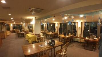 A restaurant with multiple dining tables and chairs, large windows, and hanging decorations.