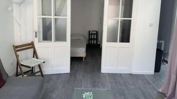 A room with a bed, a chair, and a door leading to another room. - Bright apartment downtown La Ciotat - 2 min from the port (La Ciotat)