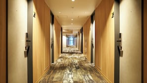 Ein Hotelgang mit Holzwandverkleidung, nummerierten Türen und einem gemusterten Teppich.