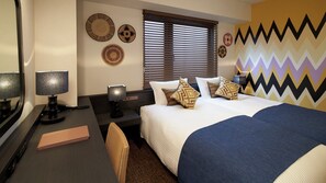 Ein Hotelzimmer mit Bett, Nachttischen, Schreibtisch, Stuhl und einem Fenster mit Jalousien.