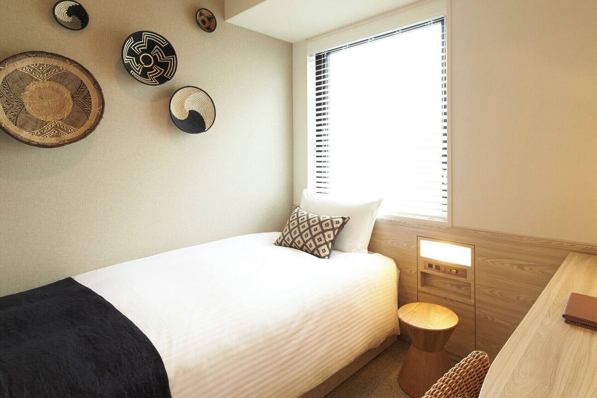 A hotel room with a bed, bedside table, lamp, and decorative wall art.