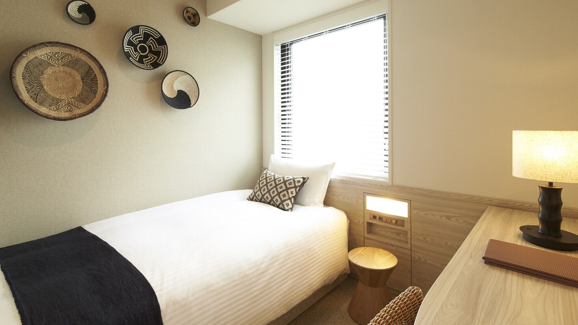 A hotel room with a bed, bedside table, lamp, and decorative wall art.