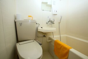 Un baño pequeño con inodoro, lavamanos y ducha.