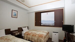 Ein Hotelzimmer mit zwei Betten, einem Fernseher, einem Schreibtisch und einem Fenster mit Aussicht.