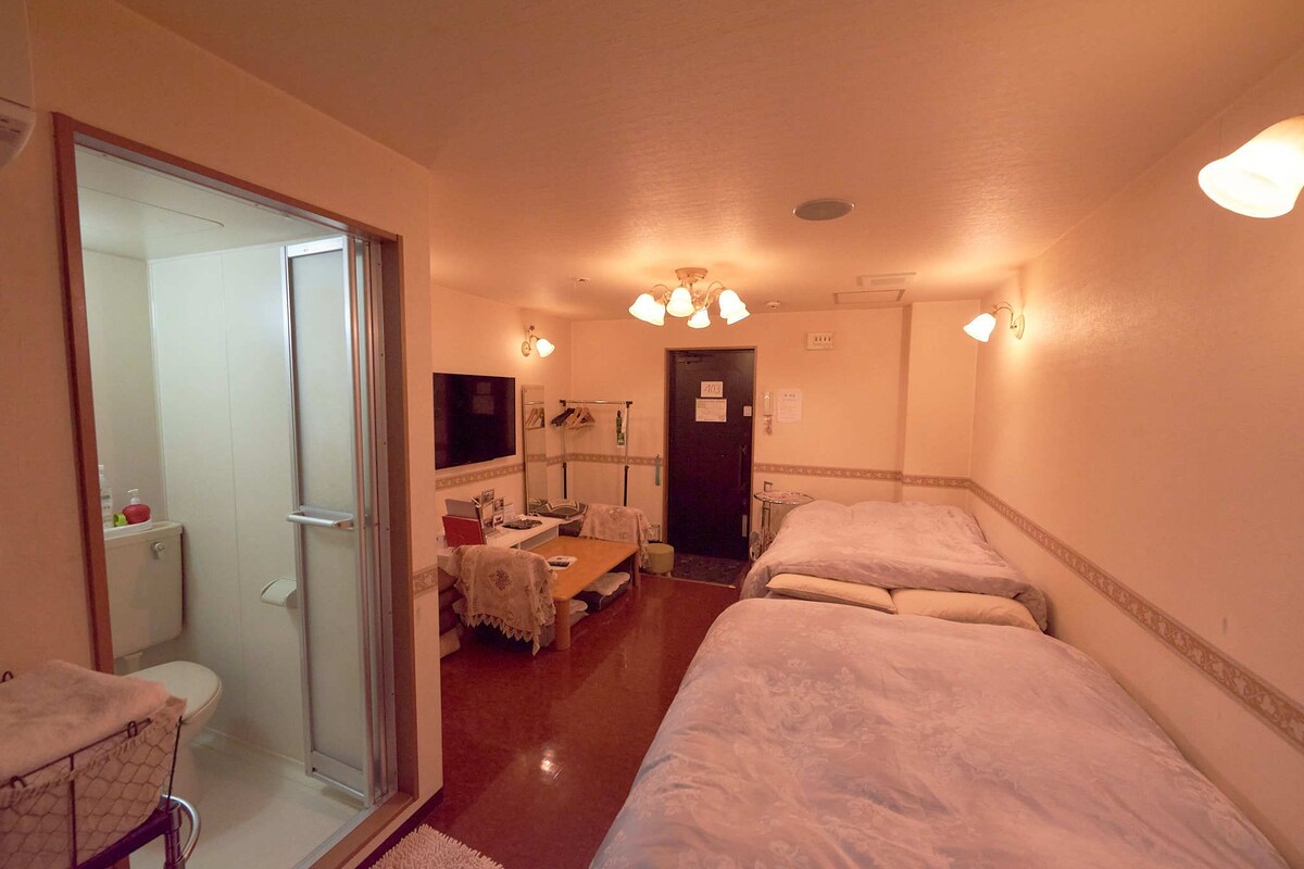 A hotel room with two beds, a bathroom, a desk, and a television.