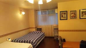 A hotel room with two single beds, a desk, a chair, a window with curtains, and three framed pictures on the wall. - Hotel 4F Macaroni (Osaka)