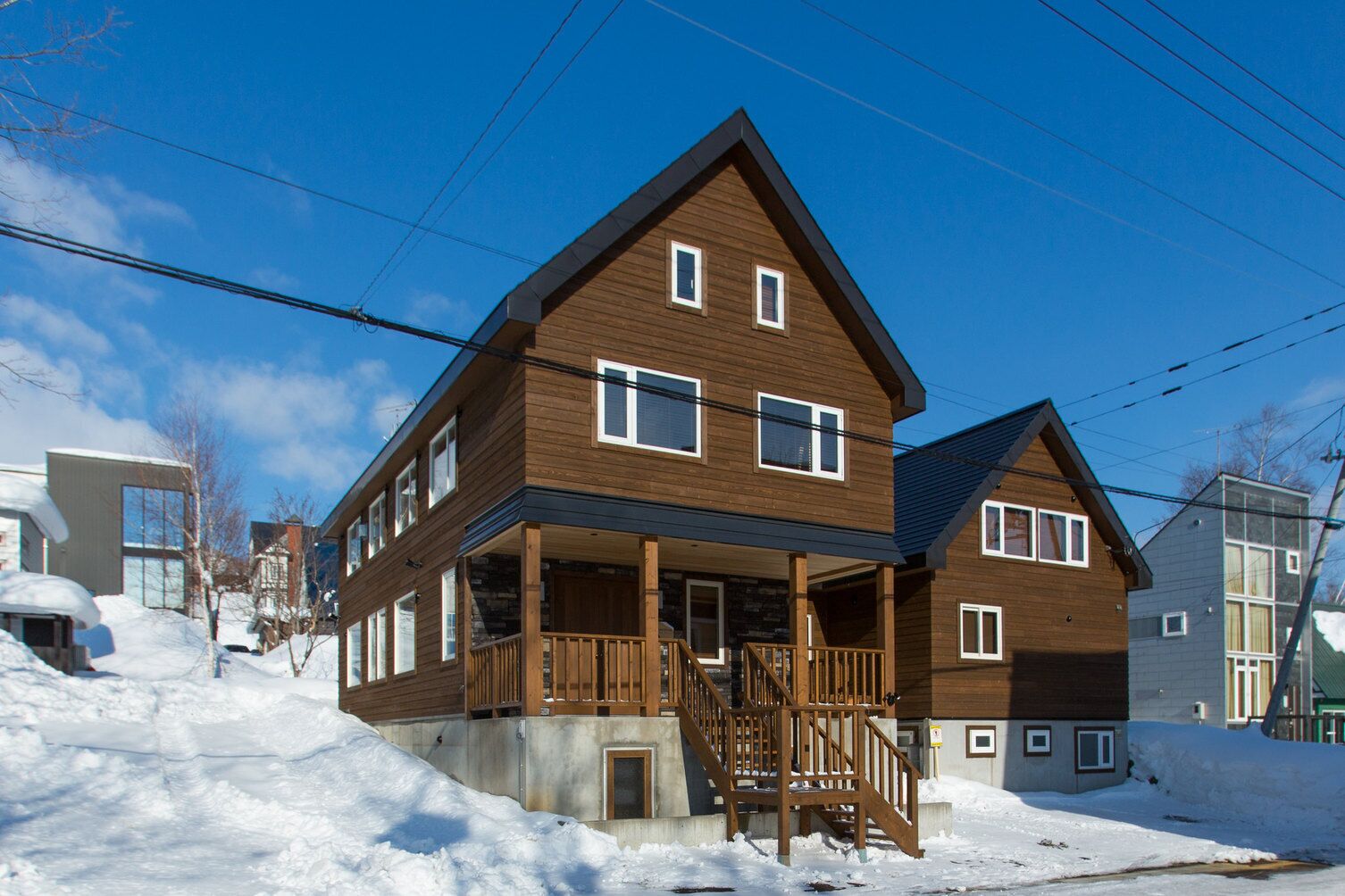 A two-story wooden house with a balcony, a porch, and a staircase leading to the entrance.