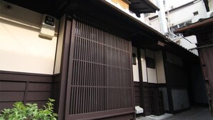 Een traditioneel Japans gebouw met een schuifdeur, een klein buitenstuk met een plant en een zichtbare airconditioning.