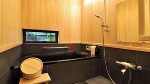 Een moderne badkamer met een zwart bad, een houten wastafelmeubel en een raam met uitzicht op groen.