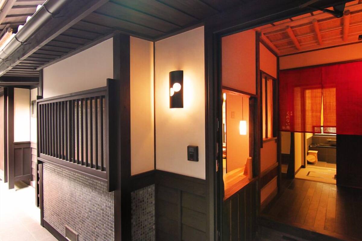A traditional Japanese interior with a wooden floor, a sliding door, and a wall-mounted light fixture.