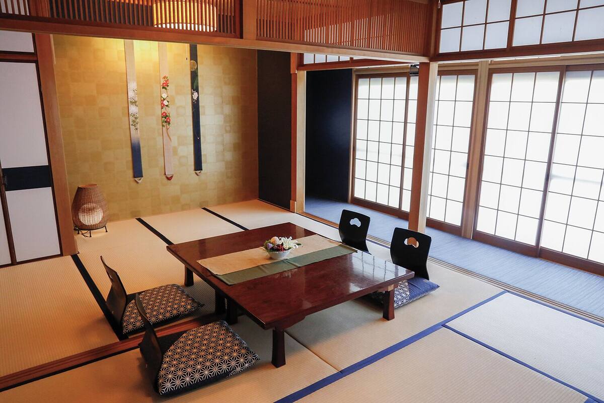 Une pièce de style japonais traditionnel, avec un sol recouvert de tatamis, une table basse et des chaises noires.