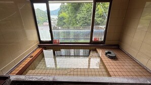 A small, tiled room with a window, a bench, and a hot tub. - Kinosaki Onsen Sanso Ashigaru Ryokan (Toyooka)