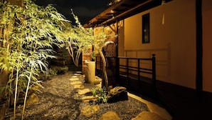 A garden pathway with stepping stones, bamboo plants, and a wooden fence. - Kuraya Senbonsanjo (Kyoto)