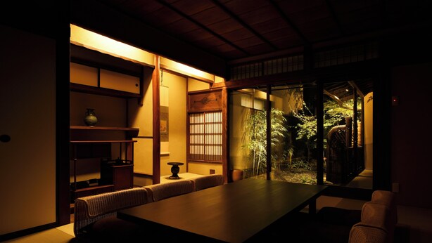 A traditional Japanese room with tatami flooring, a low table, and a view of a garden. - Kuraya Senbonsanjo (Kyoto)