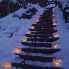 A snow-covered staircase with candles placed at intervals. - Kakeyu Onsen Shikanoya Ryokan (Ueda)